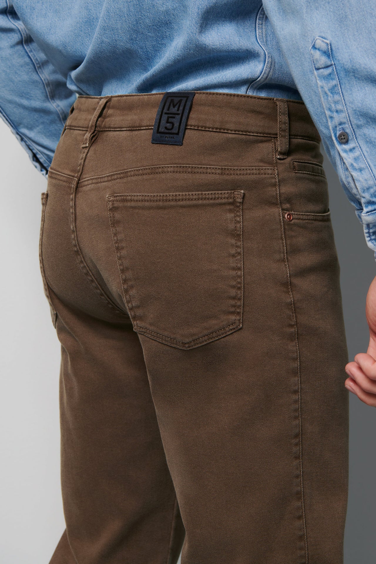 Brown pants with a visible brand label worn by a person in a blue shirt.