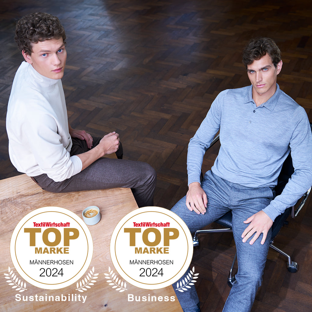 Two men sitting at a table with 'Top Marke' awards for Sustainability and Business in 2024.