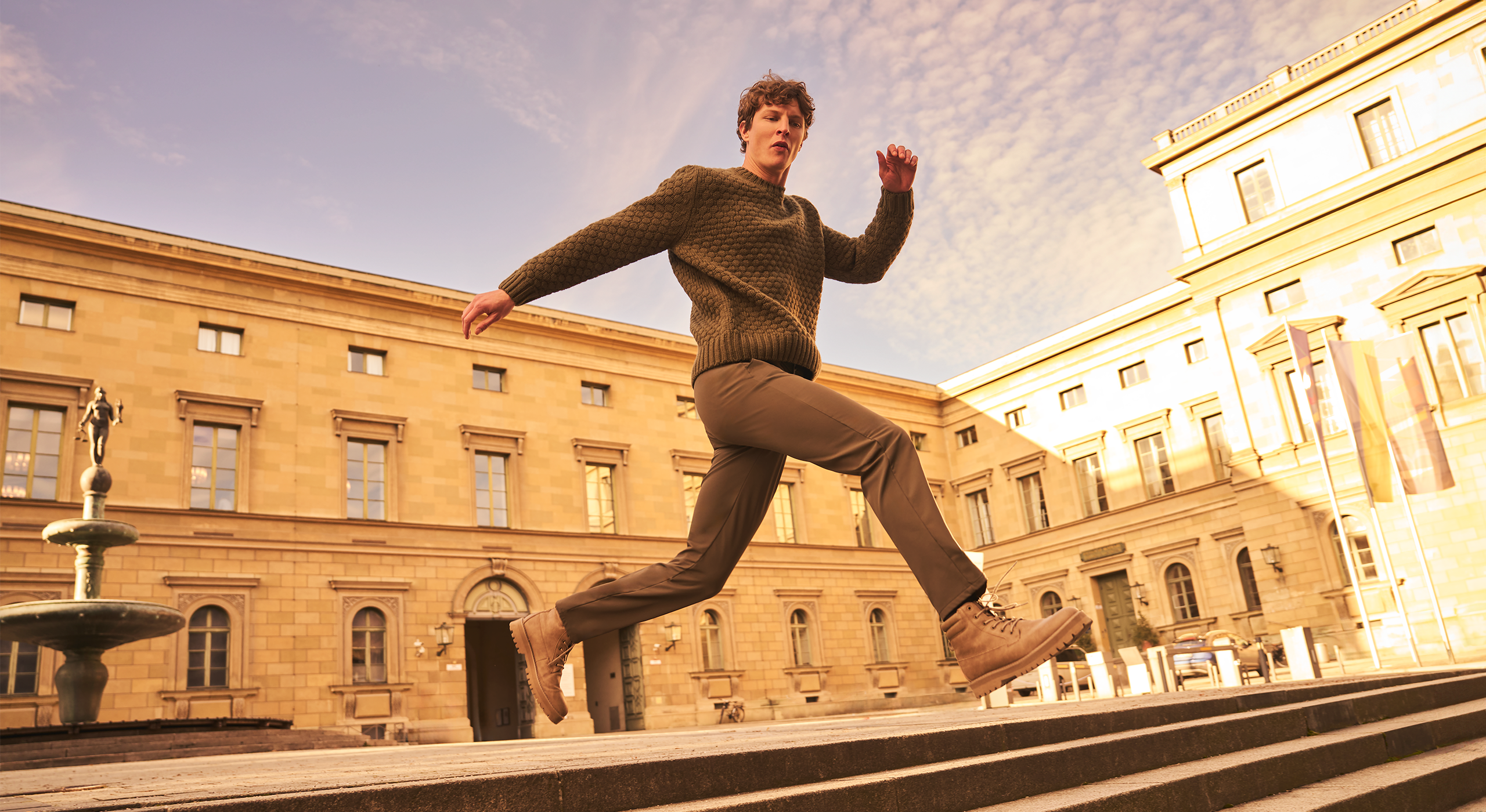 Person running in front of a classical building with a fountain